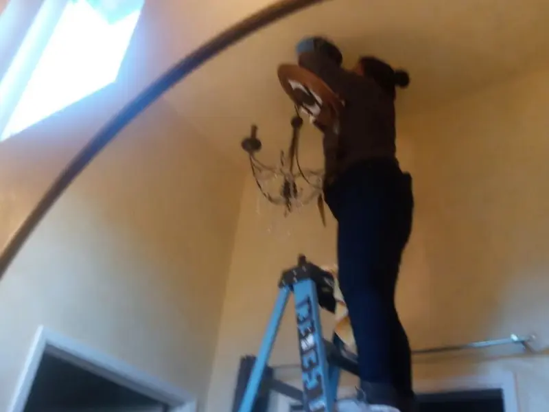 Electrician installing a chandelier in a Largo residence